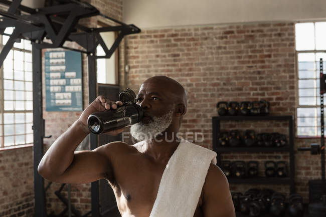 Uomo anziano stanco acqua potabile nella sala fitness . — Foto stock