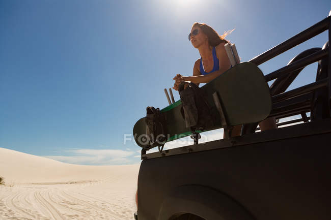 Женщина, стоящая в открытом джипе на песчаной дюне — стоковое фото