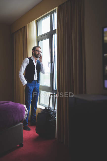Empresário falando no telefone celular no quarto de hotel — Fotografia de Stock