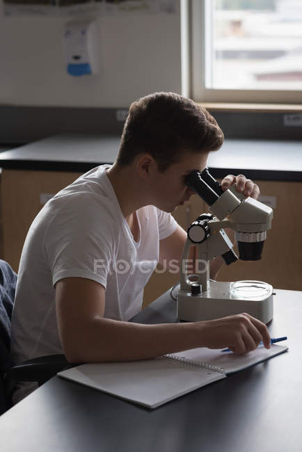 Ragazzo adolescente che sperimenta al microscopio in laboratorio all'università — Foto stock