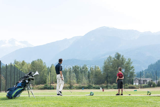 Vater und Sohn stehen an einem sonnigen Tag auf dem Golfplatz — Stockfoto