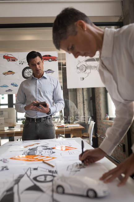 Мужские и женские автомобильные дизайнеры, работающие за столом в офисе . — стоковое фото