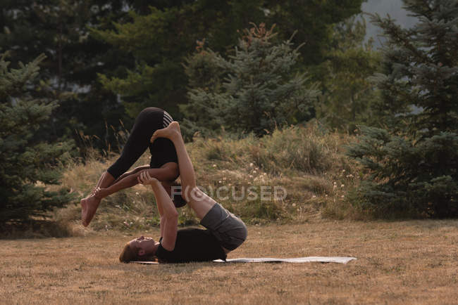 Спортивні жінки практикують акро-йогу на відкритому повітрі в сонячний день — стокове фото