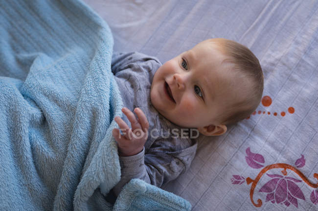Nahaufnahme eines glücklichen Babys, das sich im Bett entspannt. — Stockfoto