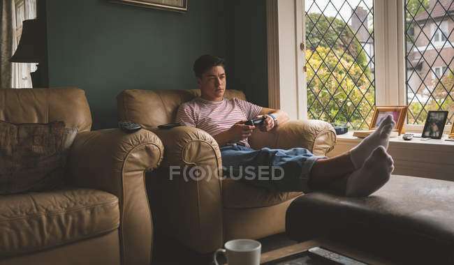 Uomo che gioca al videogioco sul divano in soggiorno a casa
. — Foto stock