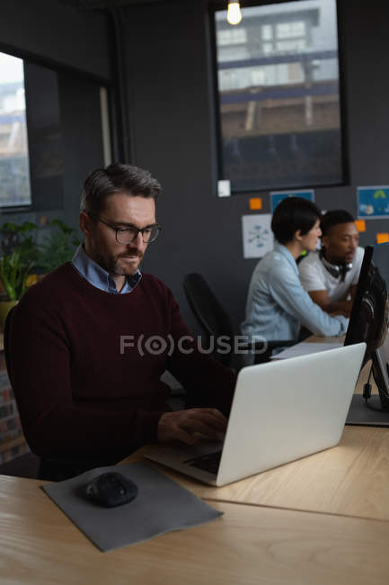 Ejecutivo masculino trabajando sobre el ordenador portátil en el escritorio en la oficina . - foto de stock