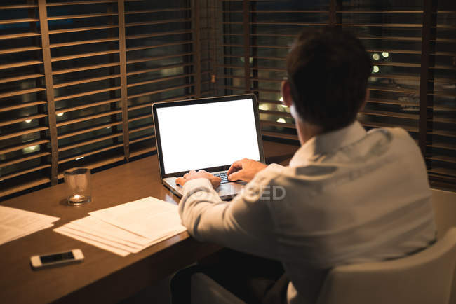 Uomo d'affari che utilizza il computer portatile alla scrivania in camera d'albergo — Foto stock