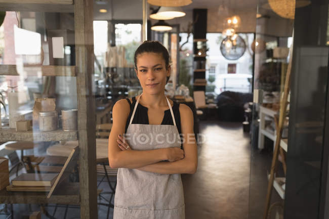 Portrait of waitress standing with arms crossed in coffee shop — Stock Photo