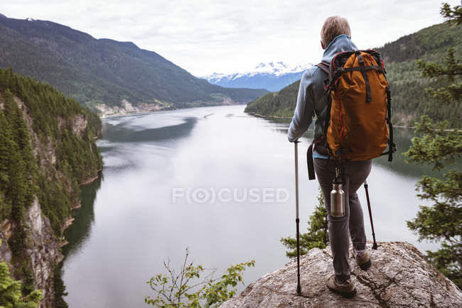 Visão traseira da mulher madura em pé na rocha e olhando para a bela montanha — Fotografia de Stock