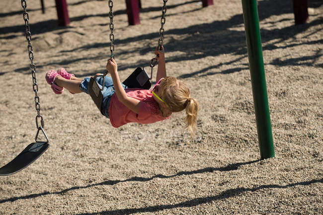 Nettes Mädchen spielt auf Schaukel im Park — Stockfoto