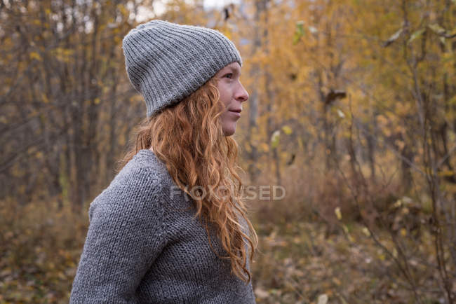 Hermosa mujer en ropa de abrigo de pie en el bosque de otoño - foto de stock
