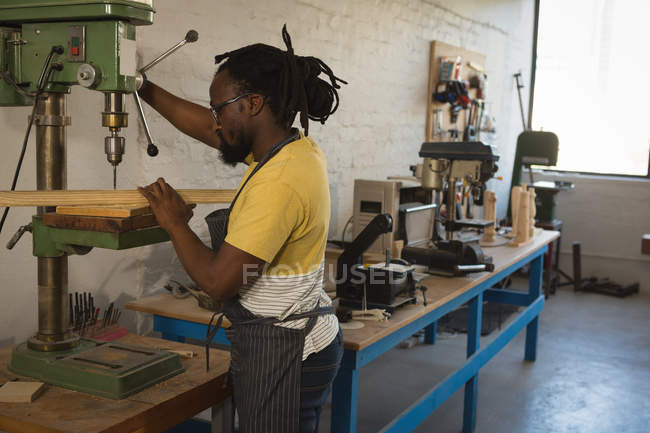 Tischler bohrt Holzplanke mit Maschine in Werkstatt — Stockfoto
