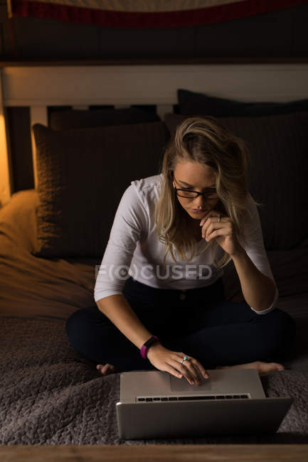 Junge Frau benutzt ihren Laptop auf dem Bett im Schlafzimmer — Stockfoto