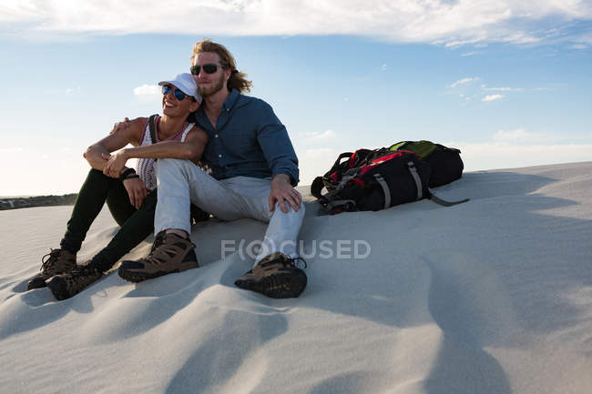 Couple relaxant sur le sable dans le désert par une journée ensoleillée — Photo de stock