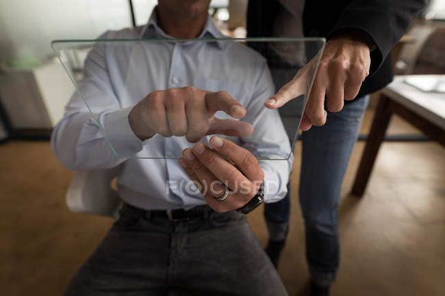 Business colleagues using glass digital tablet in office. — Stock Photo