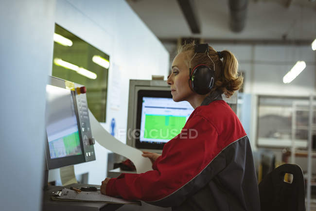 Female worker operating a machine in factory — Stock Photo
