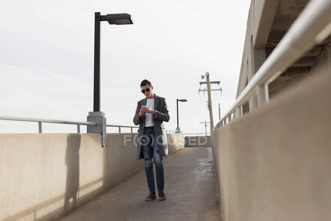 Задуманный человек, использующий мобильный телефон на мосту — стоковое фото