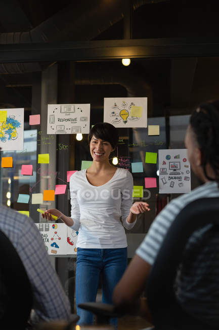 Female executive discussing with colleagues in office by wall with sticky notes. — Stock Photo