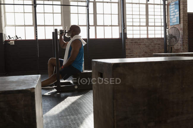 Старший чоловік п'є воду після тренування у фітнес-студії . — стокове фото