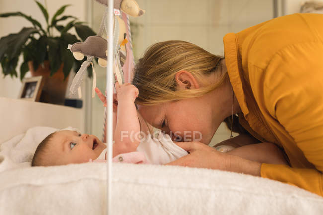 Mother playing with baby boy at home, side view. — Stock Photo
