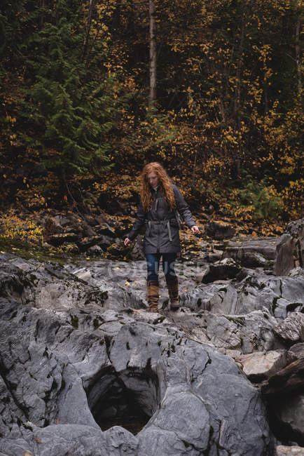 Red haired woman walking on the wet rocks — Stock Photo