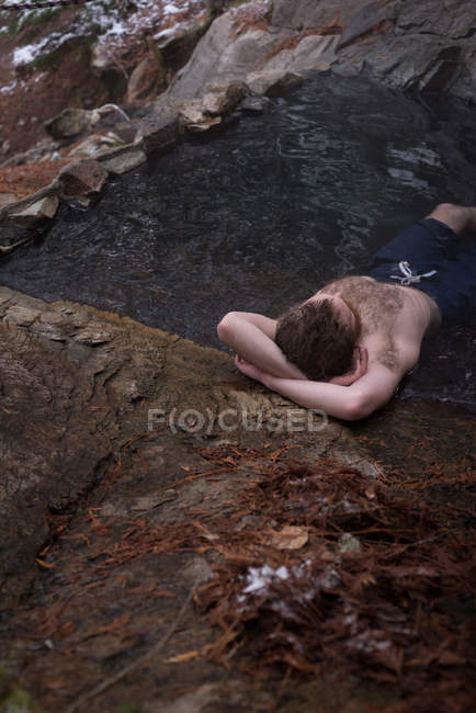 Hombre sin camisa relajándose en la primavera caliente durante el invierno - foto de stock
