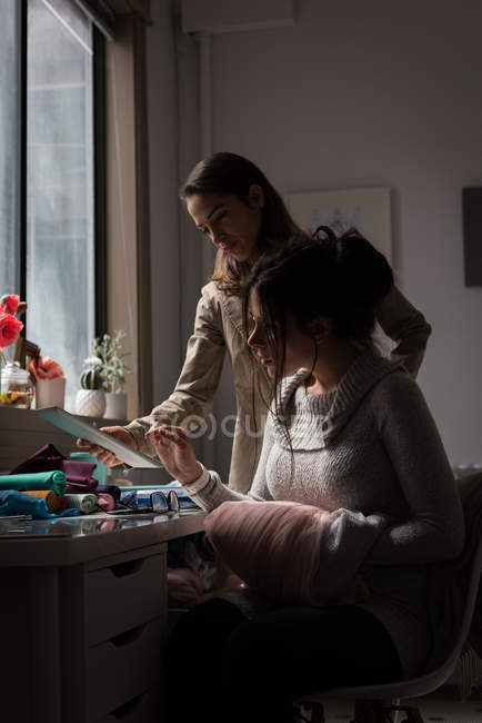 Fashion designers discussing over digital tablet in design studio. — Stock Photo