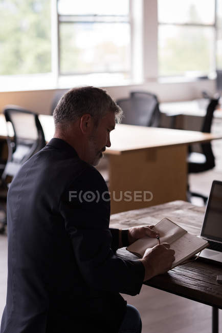 Empresário escrevendo no diário na mesa no escritório criativo — Fotografia de Stock