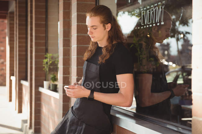 Owner using mobile phone at outside cafe — Stock Photo