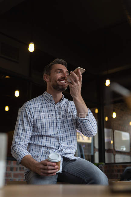 Чоловік виконавчий з кавою розмовляє на мобільному телефоні в офісі . — стокове фото