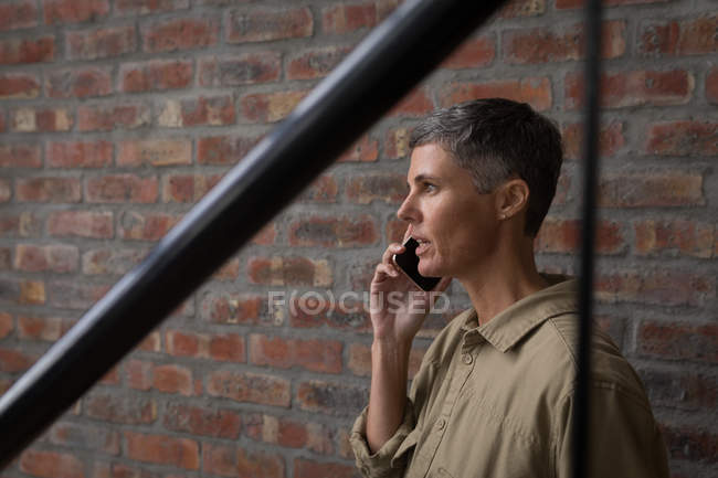 Деловая женщина разговаривает по мобильному телефону в офисе. — стоковое фото