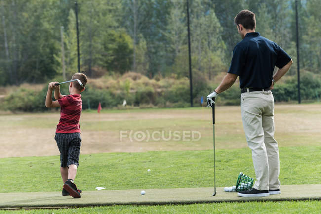 Padre e hijo jugando al golf en el campo de golf - foto de stock