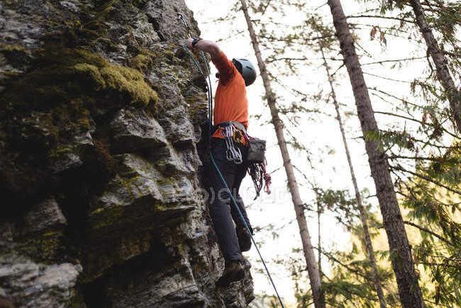 Scalatore determinato che si arrampica sulla falesia rocciosa — Foto stock