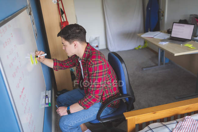 Молодой человек пишет на белой доске в интерьере комнаты . — стоковое фото