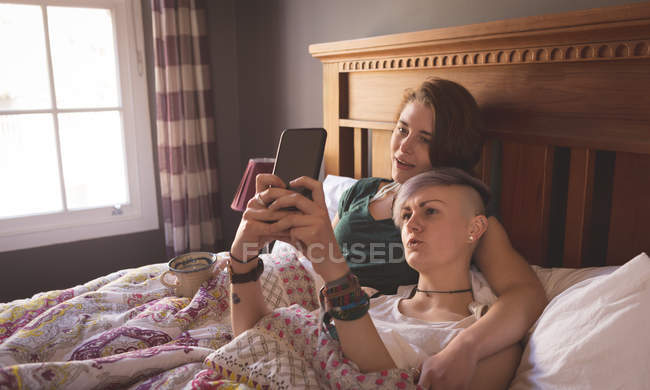 Лесбийская пара делает селфи в постели дома . — стоковое фото