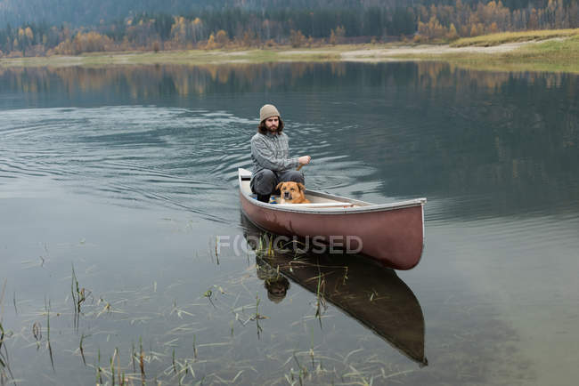 Homme aviron canot dans la rivière avec son chien — Photo de stock