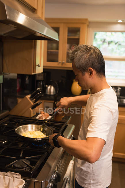 Padre preparando comida en la cocina en casa - foto de stock