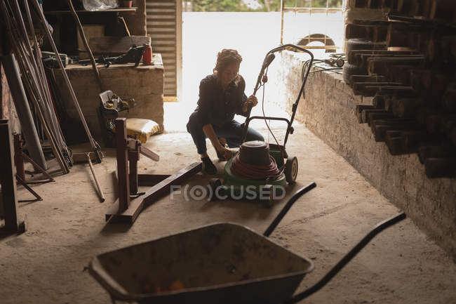 Mulher reparar cortador de grama na oficina — Fotografia de Stock