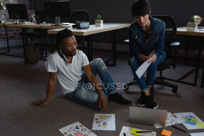 Des hommes d'affaires avec ordinateur portable discutant de documents au bureau . — Photo de stock