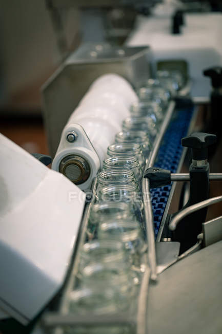 Primer plano de frascos de vidrio vacíos en la línea de producción en la fábrica de alimentos - foto de stock