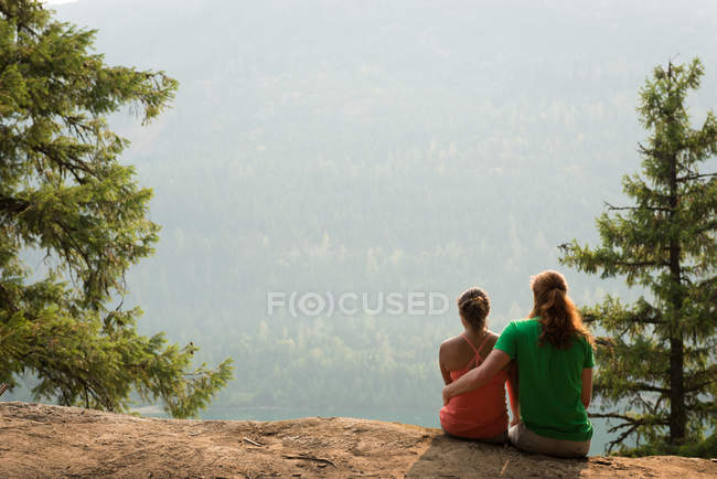 Couple sportif assis l'un près de l'autre sur le bord d'un rocher au moment de l'aube — Photo de stock