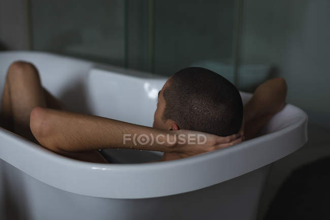 Jeune homme relaxant dans la baignoire à la salle de bain — Photo de stock