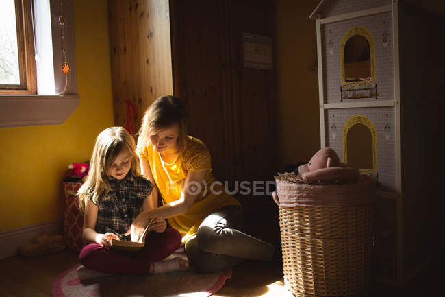 Tochter mit Mutter liest zu Hause im Schlafzimmer ein Buch — Stockfoto