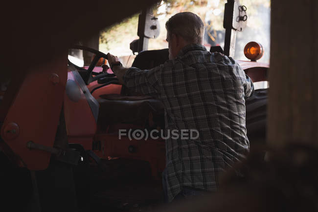 Vista traseira do agricultor que se prepara para se sentar no tractor — Fotografia de Stock