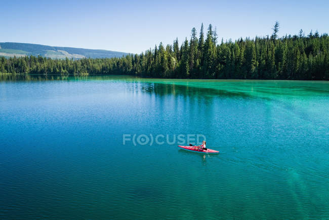 Kayaker kayak in acque turchesi poco profonde lungo la costa in una giornata di sole — Foto stock