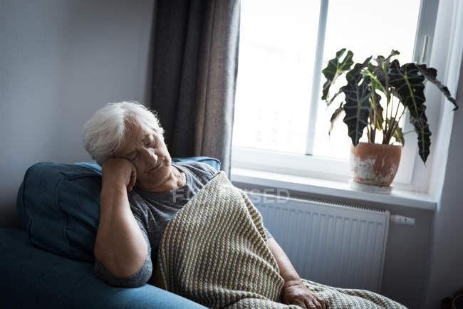 Senior mulher relaxante na poltrona na sala de estar em casa — Fotografia de Stock