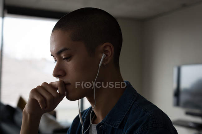 Jovem ouvindo música em fones de ouvido em casa — Fotografia de Stock