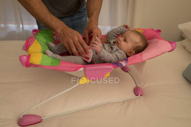 Vista cortada do pai brincando com o bebê filho na cama em casa . — Fotografia de Stock