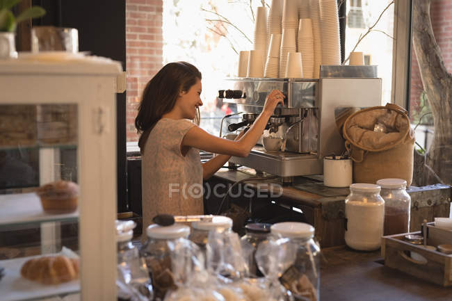 Улыбающаяся официантка делает чашку кофе в кофейне — стоковое фото