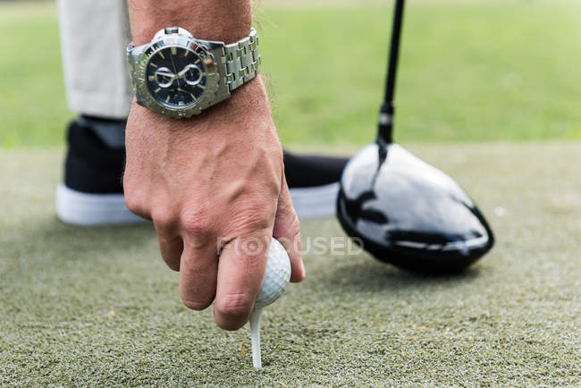 Homme ajustant la balle de golf sur le tee dans le parcours de golf — Photo de stock